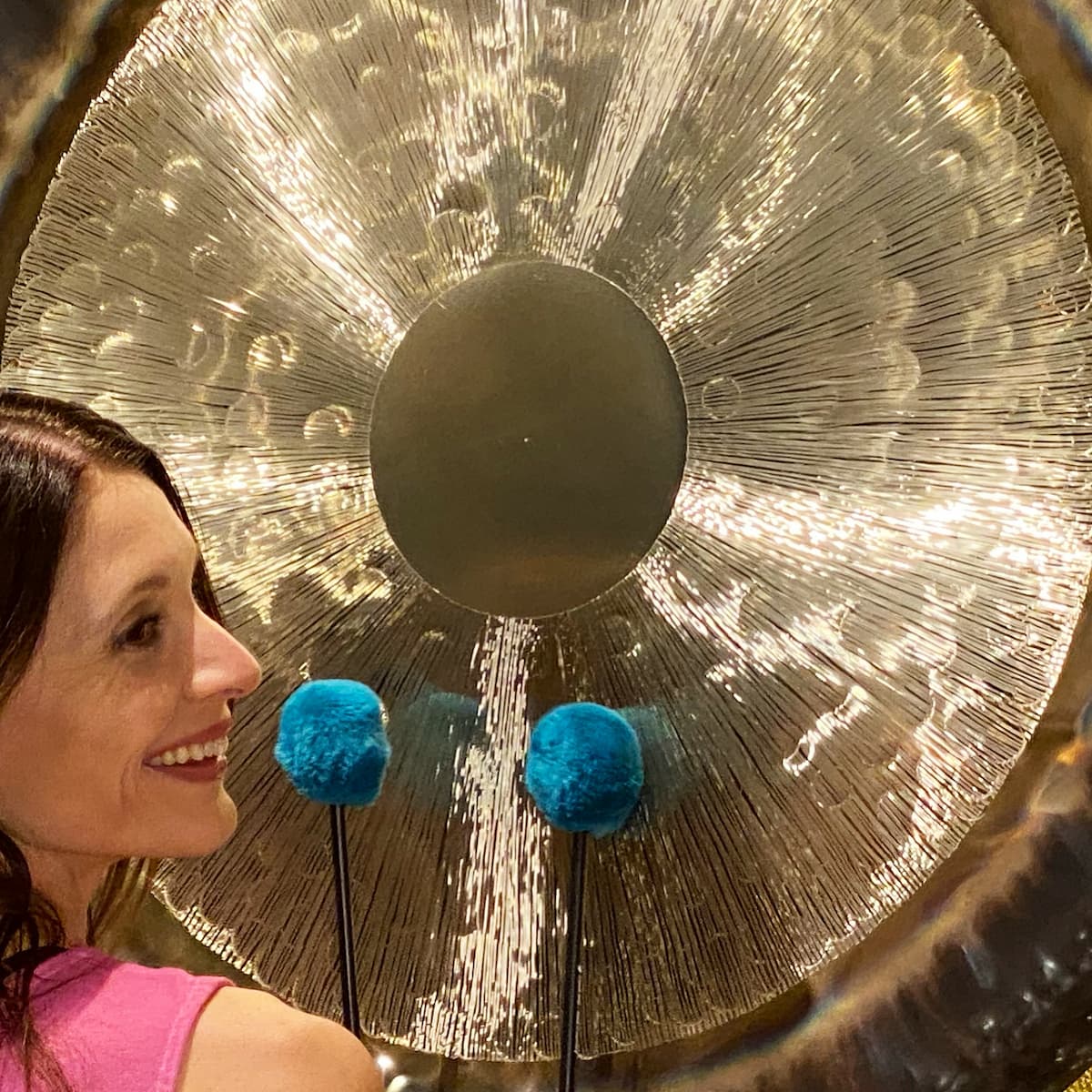 Jamie Bechtold playing large gong with two mallets.