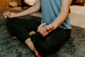 Woman-sitting-holding-crystals Woman sitting in meditation posture holding crystals.